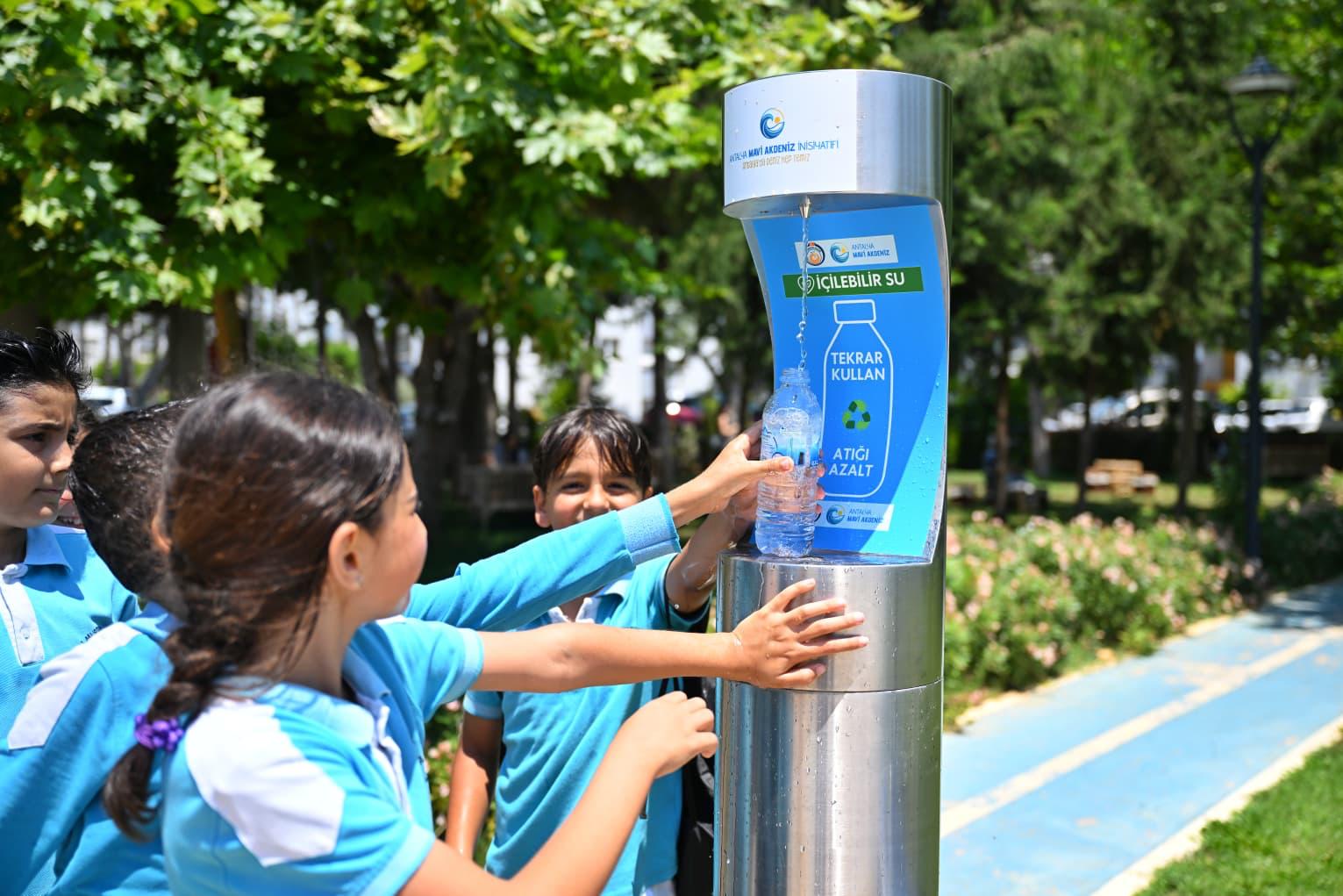 Çocuklar içme suyu çeşmesinden matarasını dolduruyor
